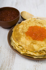 Pancakes with red caviar on a table.