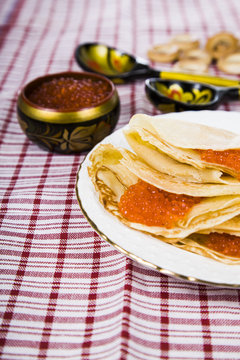 Pancakes with red caviar on a table.