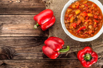 Letcho or stew with paprika and mushrooms on wooden background