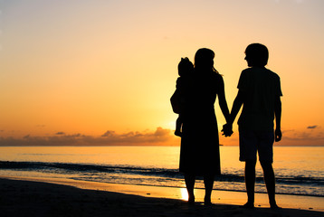 romantic couple with little child at sunset tropical beach