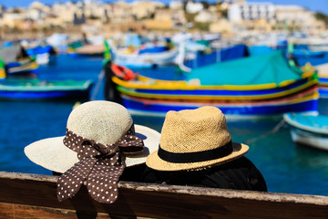 two hats with traditional maltese boats on background