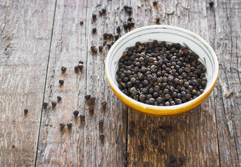 Bowl of black pepper on wooden table