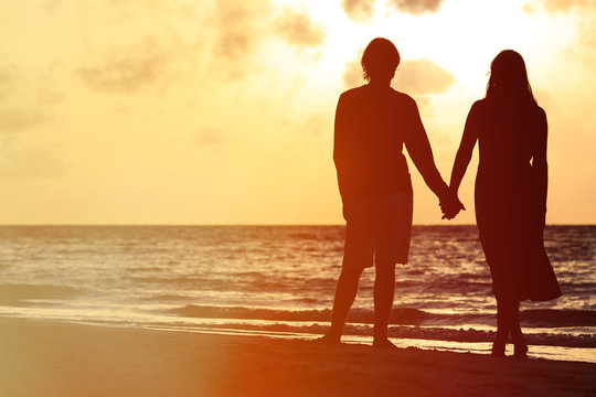 romantic couple holding hands at sunset
