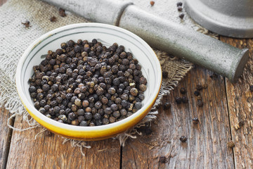 Bowl of black pepper on wooden table