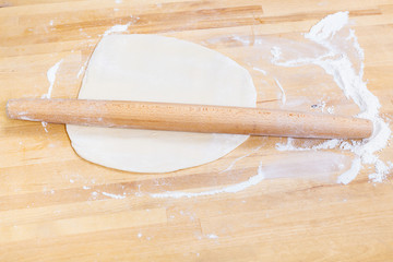 flour, rolling pin and rolled dough on table