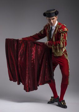Studio shot of man dressed as Spanish torero, matador, bullfighter. Performing a traditional classic bullfight, standing and holding the capote. 