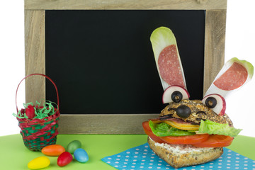 lustiges Brötchen mit leerer Tafel und Osterdeko