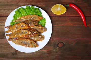 closeup of a plate with spanish boquerones fritos, battered and fried anchovies typical in Spain, on a rustic wooden table
