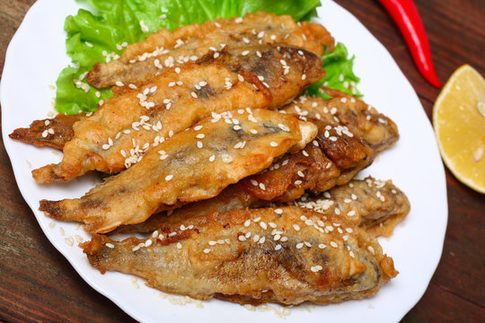 closeup of a plate with spanish boquerones fritos, battered and fried anchovies typical in Spain, on a rustic wooden table