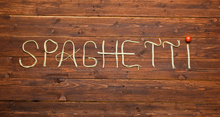 word made of spaghetti pasta on wooden background