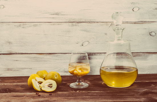 Glass of drink and carafe of alcohol tincture with quince fruits