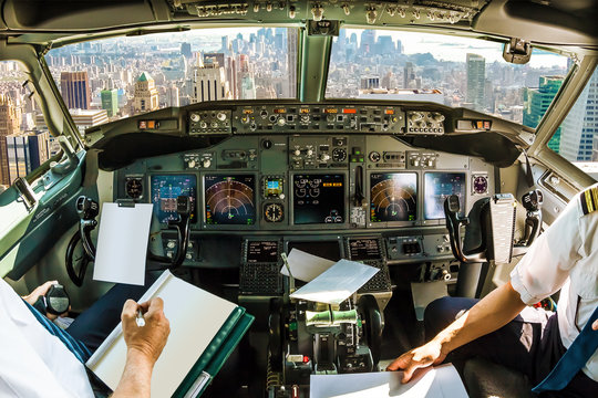 Flight in airplane cabin interior on New York skyline of United States of America.. Pilots arms and blank white papers for copy space