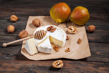 Camembert cheese with walnuts, honey and pears on rustic table