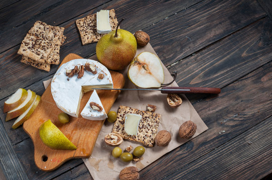 Camembert cheese with walnuts, honey and pears on rustic table. Glass of white wine. Top view