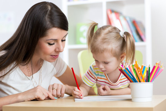 Young mother looking how her kid daughter drawing a picture
