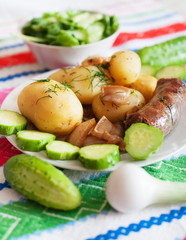 Boiled potatoes with grilled sausage and cucumber