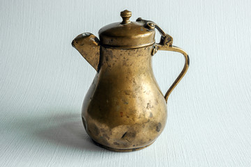 ancient bronze jug with a cover on a white structural background
