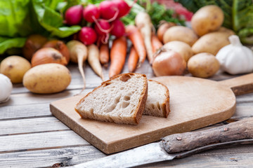 Freshly cut bread on chopping board with organic vegetables