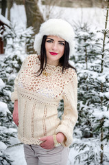 beauty girl in warm woolen sweater under snow-covered trees branches