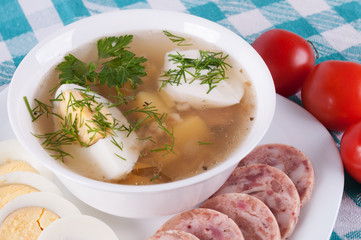 Soup with egg and slices of sausage.