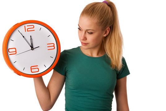 Blonde woman holding big clock in hand isolated over white.