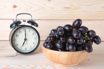 grapes in wood bowl on table with seven o'clock background