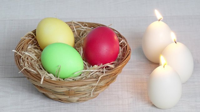 Bunte Ostereier im Korb mit Kerzen