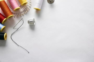 Sewing tools on white fabric background top view diagonal set - obrazy, fototapety, plakaty