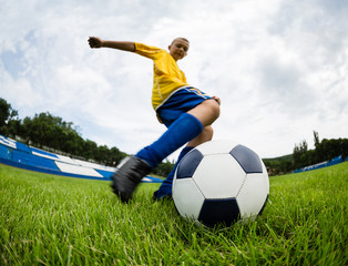 Boy soccer player hits the football ball