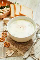 
mushroom soup with potatoes , carrots , green and white toast on a wooden background