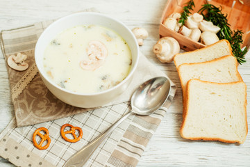 
mushroom soup with potatoes , carrots , green and white toast on a wooden background