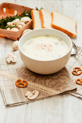 
mushroom soup with potatoes , carrots , green and white toast on a wooden background