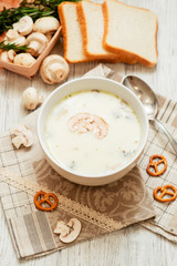 Obraz na płótnie Canvas mushroom soup with potatoes , carrots , green and white toast on a wooden background
