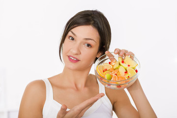 Beautiful girl holding a bowl of fresh healthy fruit salad