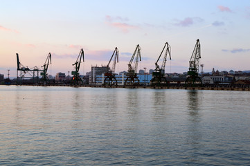 Fototapeta na wymiar Cargo docks with dark cranes’ silhouettes after sunset, Varna Harbor, Bulgaria