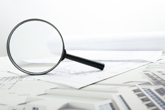 Architectural blueprints, blueprint rolls and magnifying glass on white background.