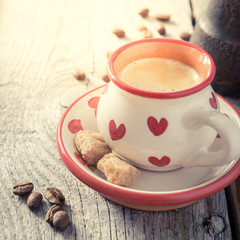 Coffee in white cup with hearts, beans, rustic wood background