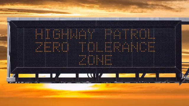 Zero tolerance highway patrol freeway sign with time lapse sunset.