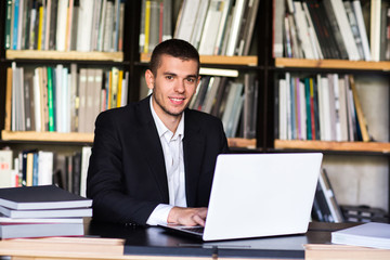 student boy working on a laptop in the library