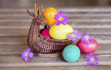 vibrant Easter Eggs in a wicker deer basket on a wooden background