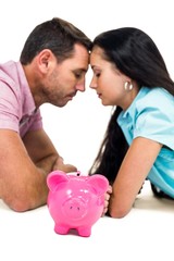 Worried couple laying on the floor face to face with piggybank