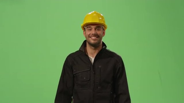 Construction worker in a hard hat is walking on a mock-up green screen in the background.Shot on RED Cinema Camera.