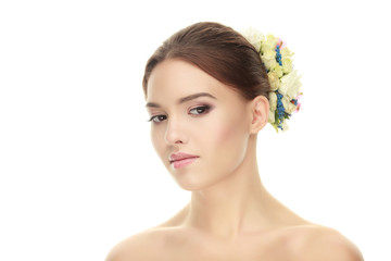 Fototapeta premium Closeup beauty portrait of adorable calm brunette woman with flower headpiece showing cute fresh makeup posing with bare shoulders on white studio background