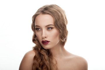 Closeup portrait of young fashionable blonde woman with wavy hairstyle showing gorgeous vintage makeup posing with bare shoulders on white studio background