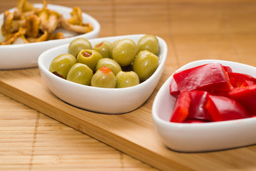 Set of starters. Pickled chanterelles, green olives and red peppers.