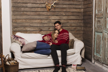 Obraz premium a beautiful couple. a love story, celebrating the New Year's holiday, Christmas and Valentine's Day. In the background christmas attributes: Christmas tree and gifts.