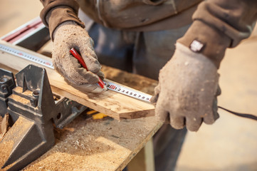 Construction Worker Using Tape Measure / Professional carpenter at work measuring wooden planks