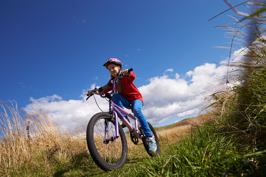 Low Angle Shot Of Girl Riding Bike Through Countryside