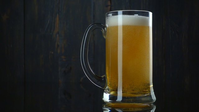 Pouring beer into glass over dark wooden background