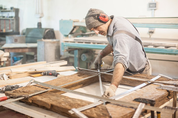 Construction Worker Using Tape Measure / Professional carpenter at work measuring wooden planks